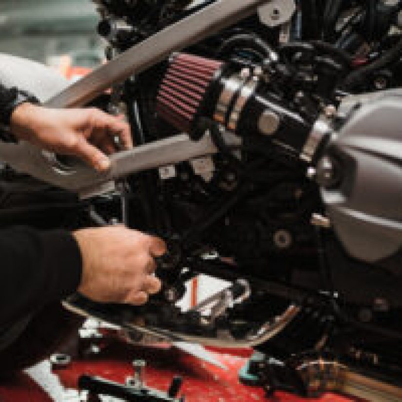 Repairman repair motorcycle, maintenance in garage. Mechanic fixing bike in a modern shop