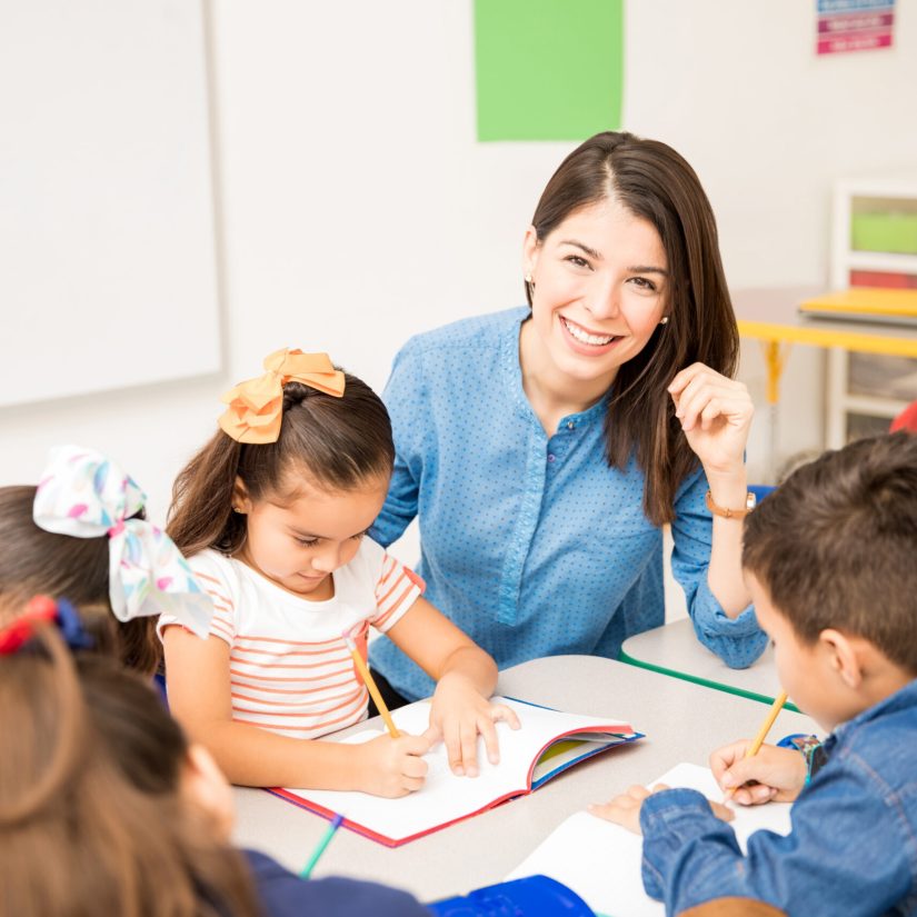 Portrait of a gorgeous Hispanic preschool teacher teaching her students in a classroom